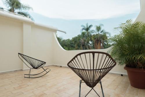 two black chairs on a balcony with palm trees at Gamma Cuernavaca Puerta Paraiso in Cuernavaca