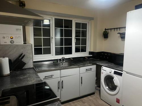 a kitchen with a sink and a washing machine at XB Property - Comfy house perfect for families contractors relocators in West Bromwich