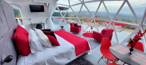 Monarca Azul Glamping في فيلا دي ليفا: غرفة نوم بسرير وكراسي حمراء في غرفة