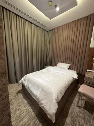 um quarto com uma cama branca e uma cadeira em شقة فاخرة في برج جلامور em Riyadh