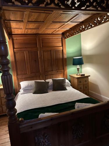 a bedroom with a large bed with a wooden headboard at The Buxton Retreat A Luxurious 3-Storey Townhouse with Four Poster Bed and Double Jacuzzi Bath" in Buxton