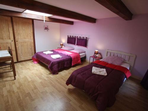 Cette chambre comprend 2 lits dans une chambre dotée de murs violets et de parquet. dans l'établissement Gîte spacieux avec terrasse, 3 chambres, équipements bébé, à 16 km de Gérardmer - FR-1-589-23, à Aumontzey