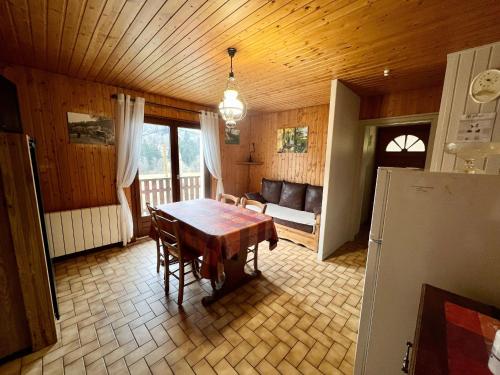 une salle à manger avec une table et un canapé dans l'établissement Chalet cosy en bordure de forêt avec wifi, terrasse et équipements complets à Rochesson - FR-1-589-235, à Rochesson