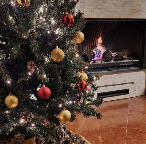 a christmas tree in a living room with a fireplace at Las Golondrinas de Henche 