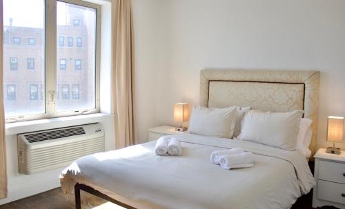 a bedroom with a large white bed with towels on it at 10 Minutes from NYC - Astoria LIC CityView in Steinway
