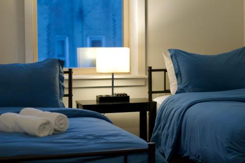 a bedroom with two beds and a lamp on a table at 10 Minutes from NYC - Astoria LIC CityView in Steinway