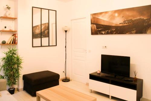 uma sala de estar com uma televisão de ecrã plano numa parede branca em Cosy 38 m love nest near Centquatre-Paris em Paris