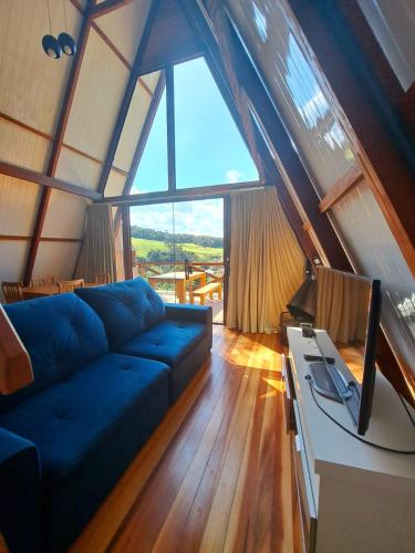 a living room with a blue couch and a tv at Chalés Roma in Santo Antônio do Pinhal