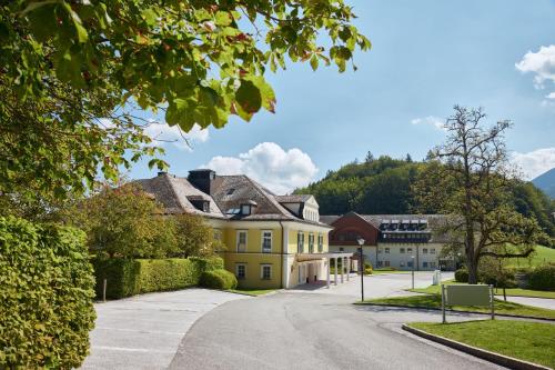 a yellow house in the middle of a street at Arabella Jagdhof Resort am Fuschlsee, a Tribute Portfolio Hotel in Hof bei Salzburg
