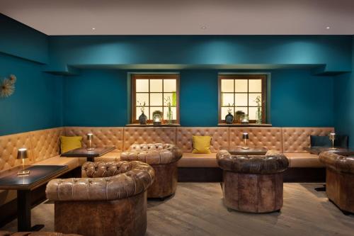 a restaurant with blue walls and tables and stools at Arabella Jagdhof Resort am Fuschlsee, a Tribute Portfolio Hotel in Hof bei Salzburg