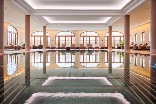 una piscina cubierta con agua en un edificio en Arabella Jagdhof Resort am Fuschlsee, a Tribute Portfolio Hotel, en Hof bei Salzburg