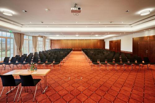 an empty conference room with chairs and tables and a projector at Arabella Jagdhof Resort am Fuschlsee, a Tribute Portfolio Hotel in Hof bei Salzburg