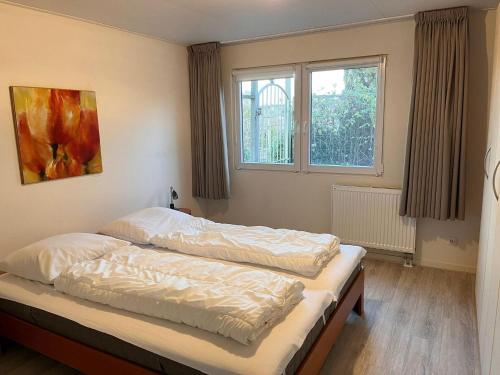 a bedroom with two beds and a window at Bungalow in Makkum near Lake Beach in Holle Poarte