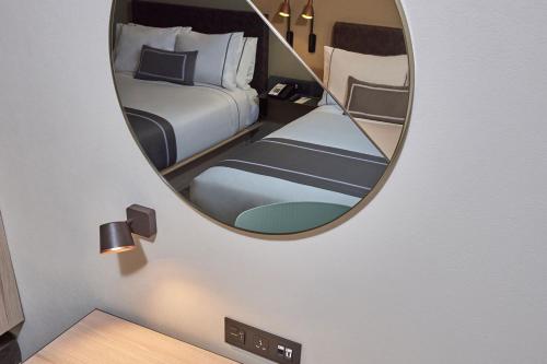 a mirror in a room with a bedroom with a bed at City Express Plus by Marriott Cancun Aeropuerto Riviera in Cancún