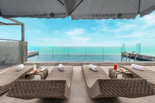 a table with chairs and a view of the ocean at Mangata Beachfront Hotel in Da Nang