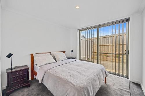 a bedroom with a bed and a large window at Petite Retreat in Cape Paterson