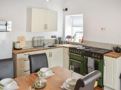 a kitchen with a table and a green oven at Cozy Cow Cottage in Belford