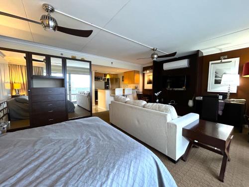 ein Schlafzimmer mit einem weißen Bett und ein Wohnzimmer in der Unterkunft Ilikai Apt 2127 - Spacious Studio with Spectacular Ocean & Harbor Views in Honolulu