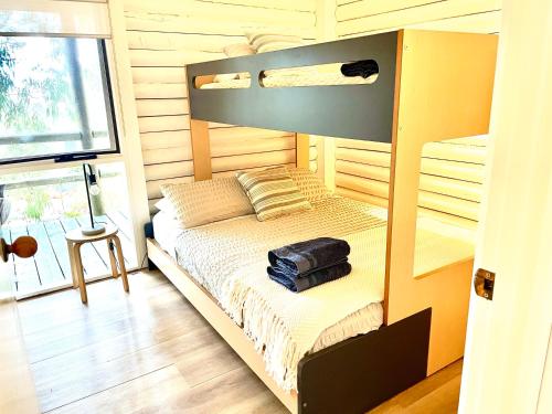a bedroom with a bunk bed with a suitcase on it at Lorne Groovy Ocean View Log House, Pet Friendly, FREE WIFI wine & chocolates kangaroos in the evening in Lorne