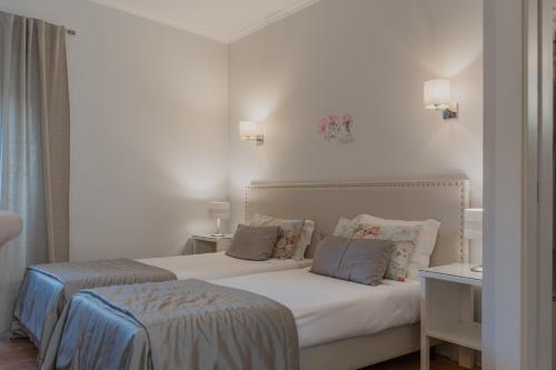 a bedroom with two beds with white walls at Hotel Casa da Nora in Leiria