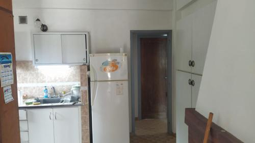 La cuisine est équipée d'un réfrigérateur blanc et d'un évier. dans l'établissement Casa para hasta 6 personas, à Santa Teresita