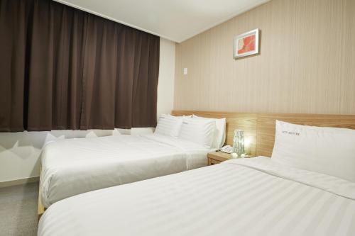 Una habitación de hotel con dos camas y una ventana. en Top Hotel & Residence, en Seúl