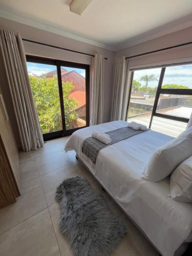 um quarto com uma cama grande e uma janela grande em Vigne Palm Inn apartment em Gqeberha