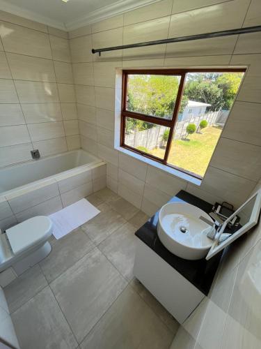 a bathroom with a sink and a toilet and a window at Vigne Palm Inn apartment in Gqeberha