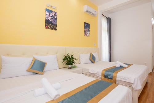 deux lits dans une chambre aux murs jaunes dans l'établissement VILLA CHERRY Vung Tau, à Vung Tau