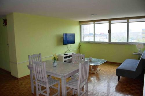 a living room with a table and chairs and a television at Depto Espacioso con hermosa vista a min del Centro Histórico de la Cdmx in Mexico City