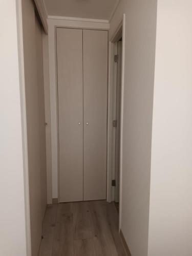 an empty hallway with white cabinets and wooden floors at Grato y Bello departamento in Quilpué