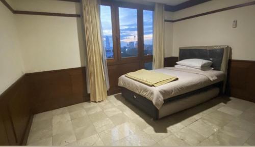 ein Schlafzimmer mit einem Bett und einem großen Fenster in der Unterkunft Park Royale Apartments, Senayan, Jakarta in Jakarta