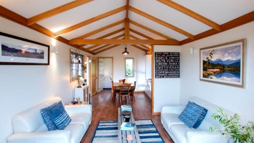 a living room with white couches and a table at Wanderers Cottage in Woodbridge