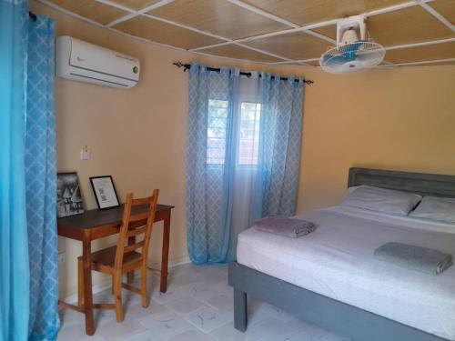 a bedroom with a bed and a table and a desk at Riverside Lodge Bansang 