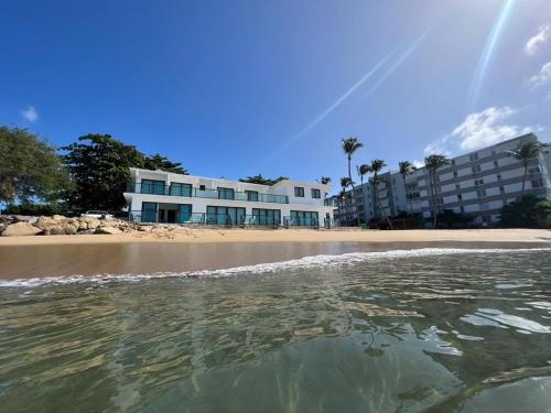 a view of the beach with a building in the background at 1 Corcega Beachfront Suites in Rincon