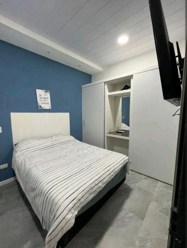 a bedroom with a bed and a blue wall at Casita de encantó en Colonia in Colonia del Sacramento