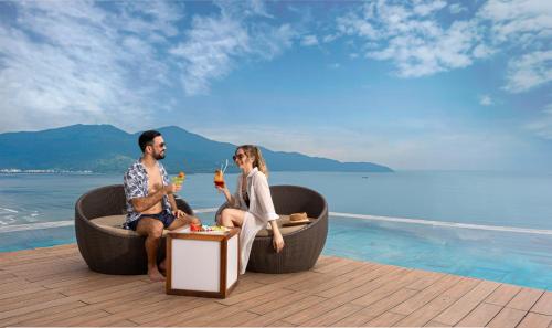 a man and a woman sitting in a round tub next to the water at A La Carte Da Nang Beach in Danang