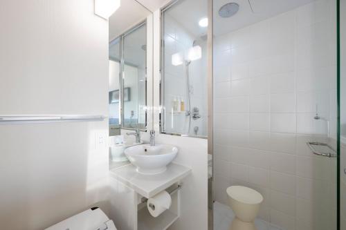 a white bathroom with a sink and a toilet at remm Akihabara in Tokyo