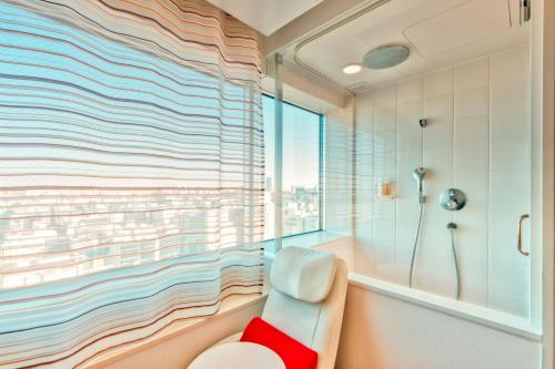 uma casa de banho com uma banheira e um chuveiro com uma janela em remm Akihabara em Tóquio