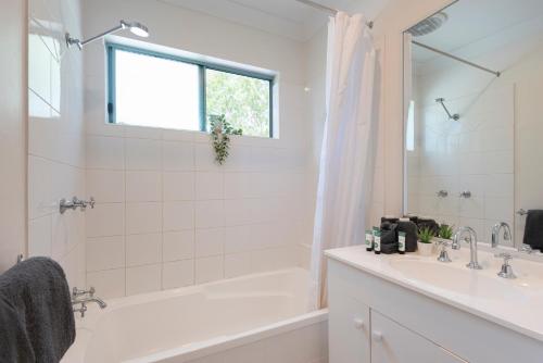 a white bathroom with a tub and a sink at Sunset Waters 1 by HamoRent on Hamilton Island in Hamilton Island