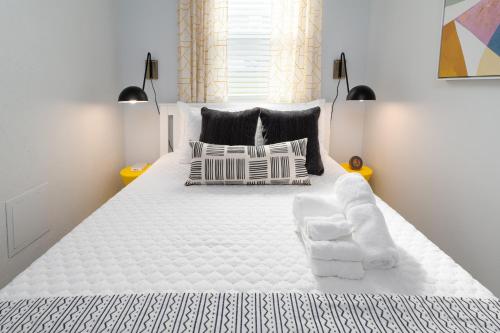 um quarto com uma grande cama branca com almofadas em Be A Nomad Beachside Apartments em Jacksonville Beach