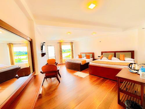 Cette grande chambre comprend deux lits, une table et des chaises. dans l'établissement Eden Hill Hotel, à Nuwara Eliya