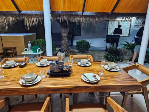 einem Holztisch mit Tellern und Geschirr darauf in der Unterkunft White house 36 Hatyai in Hat Yai