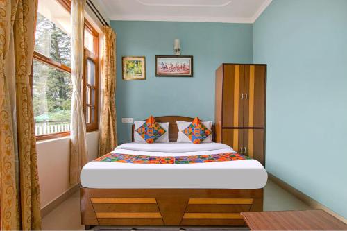a bedroom with a bed in a room with a window at Hotel Anuj Regency in Dharamshala