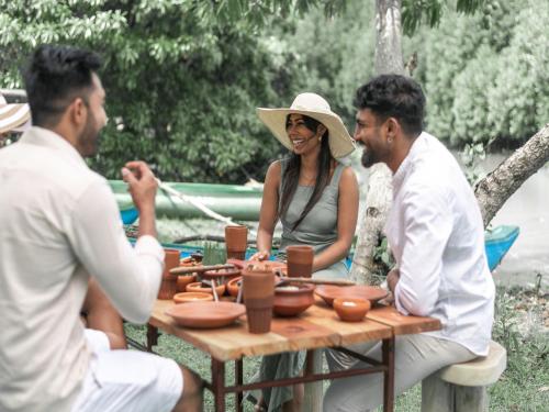 a group of people sitting around a wooden table at Sun Siyam Pasikudah in Pasikuda