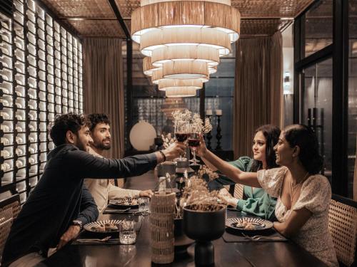 a group of people sitting around a table in a restaurant at Sun Siyam Pasikudah in Pasikuda