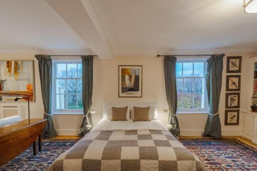 um quarto com uma cama e duas janelas em Stunning 6-bedroom countryside home em Reading