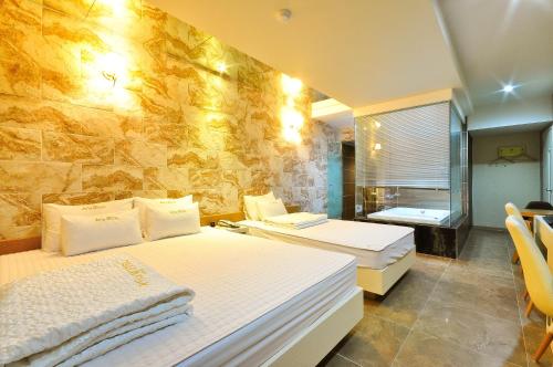 a bedroom with two beds and a stone wall at Boutique Hotel Aria Nampo in Busan