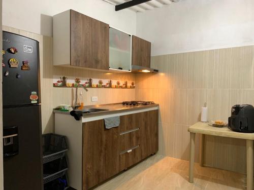 a kitchen with wooden cabinets and a black refrigerator at Habitación para 1-4 personas in Ibagué