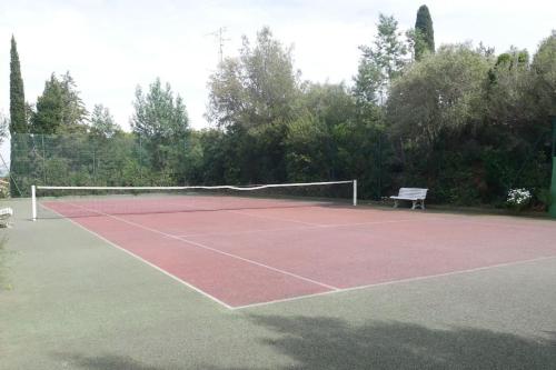a tennis court with a bench and a net at APPT Cosy entier avec piscine in Toulouse
